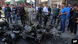Iraqi security forces and civilians inspect the site of a deadly car bomb explosion, in Baghdad, Iraq, May 30, 2017.