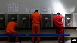 FILE - Detainees talk on telephones at the Adelanto ICE Processing Center in Adelanto, Calif., Aug. 28, 2019. 