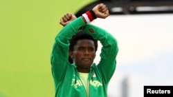 FILE - Silver medalist Feyisa Lilesa of Ethiopia crosses his wrists in an attempt to draw global attention to recent deadly protests in his home region, Oromia, after the men's marathon at the 2016 Summer Olympics.