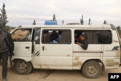 A rebel fighter stands near a bus transporting evacuees from rebel-held eastern Aleppo, upon their arrival to an area on the western edge of Aleppo city which is held by insurgents, in Syria Dec. 16, 2016.