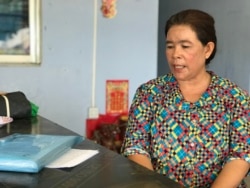 Long Sokunthy, a land activist, sits in front of a blue folder with charges and pending cases against her at her home in O'Chrov district's O' Beichoan commune, Banteay Meanchey, Cambodia, May 26, 2020. (Hul Reaksmey/VOA Khmer)