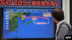 A pedestrian looks at a television screen displaying a map of Japan, right, and the Korean Peninsula in Tokyo, following a North Korean missile test that passed over Japan, Sept. 15, 2017.