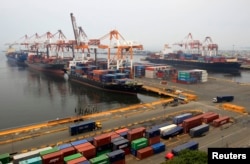 FILE - Cargo vessels wait to unload containers, while docked at the port in Manila, Aug. 20, 2014.