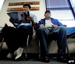 FILE - A Salvadoran national, left, accompanied by a friend, waits in the lobby of the Comite Hispano de Virgina, in Falls Church, Virginia, Nov. 11, 2002, to get help with his US immigration paperwork to extend his Temporary Protected Status (TPS).