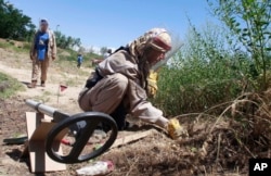 FILE - A de-miner of the Halo Trust, a British charity that specializes in the removal of land mines, searches for mines in Bagram, north of Kabul, Afghanistan, June 10, 2009.
