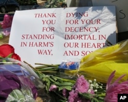 A sign of thanks rests against a traffic light pole at a memorial outside the transit center in Portland, Ore., May 27, 2017. People stopped with flowers, candles, signs and painted rocks for two bystanders who were stabbed to death Friday while trying to