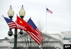 FILE - A lamp post is adorned with a Chinese national flag in between two U.S. flags in front of the White House in Washington, D.C., Jan. 17, 2011, in honor of a visit to the U.S. by Chinese President Xi Jinping. Departing from established protocol, President-elect Donald Trump has not committed himself to continue the "One China" policy followed by previous administrations.