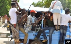 FILE - Vigilantes and local hunters armed with machetes and guns shout slogans as they gather outside the Emir's palace in Maiduguri, Nigeria, Sept. 4, 2014.