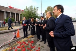 Turkish Prime Minister Ahmet Davutoglu, third right, his wife Sare Davutoglu, third left, his deputies Yalcin Akdogan, second right, and Cevdet Yilmaz, right, pray at the site of an explosion in Ankara, Turkey, Oct. 13, 2015.