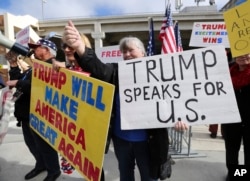 A woman gives a thumbs up as people in a passing car honk as demonstrators in favor of President Donald Trump's executive order banning travel to the U.S. from seven primarily Muslim nations stand across the street from the Tom Bradley International Terminal at Los Angeles International Airport, Feb. 4, 2017.