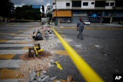 A pedestrian walks past a barricade set up by anti-government demonstrators on the second day of a 48-hour general strike in protest of government plans to rewrite the constitution, in Caracas, Venezuela, July 27, 2017.