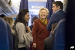 Democratic presidential nominee Hillary Clinton, center, speaks to aides, including Huma Abedin, left, aboard her campaign plane at Westchester County Airport in White Plains, N.Y., Oct. 22, 2016.