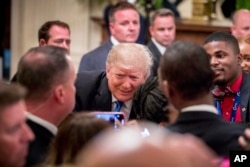 President Donald Trump takes a photograph with a member of the audience after speaking at the 2018 Young Black Leadership Summit in the East Room of the White House, Oct. 26, 2018, in Washington.