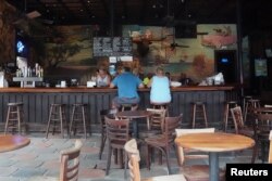 People sit at the bar of a mostly empty The Bull bar on Duval Street following Hurricane Irma in Key West, Fla., Sept. 26, 2017. A month later, tourism hasn't fully recovered.