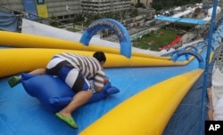 A man slides down a 22-meter-high and 300-meter-long water slide during the event called Bobsleigh in Seoul, South Korea, Aug. 19, 2017. The water slide is set up to promote the 2018 Pyeongchang Winter Olympic Games.
