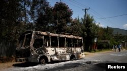 Men walk past a bus that was torched during protests in the town of Sebeta, Oromia region, Ethiopia, Oct. 8, 2016.