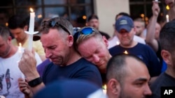 Paul Cox, right, leans on the shoulder of Brian Sullivan, as they observe a moment of silence during a vigil for a fatal shooting at an Orlando nightclub, June 12, 2016, in Atlanta, Georgia.