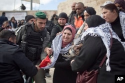 Israeli police officers try to remove a Palestinian flag from Palestinian women protesting outside the Damascus Gate in Jerusalem's Old City, Dec. 7, 2017.