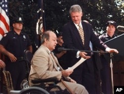 Former President Clinton gestures toward former White House press secretary James Brady in 1998 outside the White House, where he called on Congress to extend the Brady gun law.