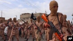 FILE -- In this photo released on April 25, 2015 by a militant website, which has been verified and is consistent with other AP reporting, young boys known as the "lion cubs" hold rifles during a parade after graduating from a religious school in Tal Afar, Iraq.