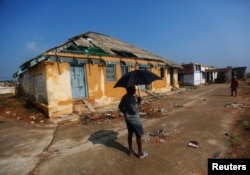 FILE - A man stands in front of a damaged house after Cyclone Phailin hit Gopalpur village, in Ganjam district in the eastern Indian state of Odisha, Oct. 14, 2013.