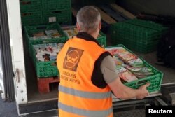 FILE – A volunteer loads a truck with food goods donated by a supermarket to charity organizations in l'Hay-les-Roses, France, May 26, 2015. France is cracking down on food waste with legislation banning big supermarkets from destroying unsold but edible food.