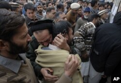 FILE - Pakistanis mourn over the death of their children at an entry gate of the Army Public School, attacked by Taliban militants, as they gather in Peshawar, Pakistan, Dec. 20, 2014.