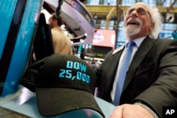 FILE- Trader Peter Tuchman smiles as he poses with an old "Dow 25,000" hat on the New York Stock Exchange trading floor, Jan. 30, 2019.