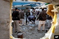 FILE - Pakistani security officials examine the site of a suicide attack in Mardan, Pakistan, Dec. 29, 2015.
