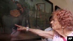 Audey Elliot of Adelaide, Australia, right, 91, touches a painting depicting Khmer Rouge torture as she tours in the former Khmer Rouge's notorious S-21 prison now known as the Tuol Sleng genocide museum in Phnom Penh, file photo. 