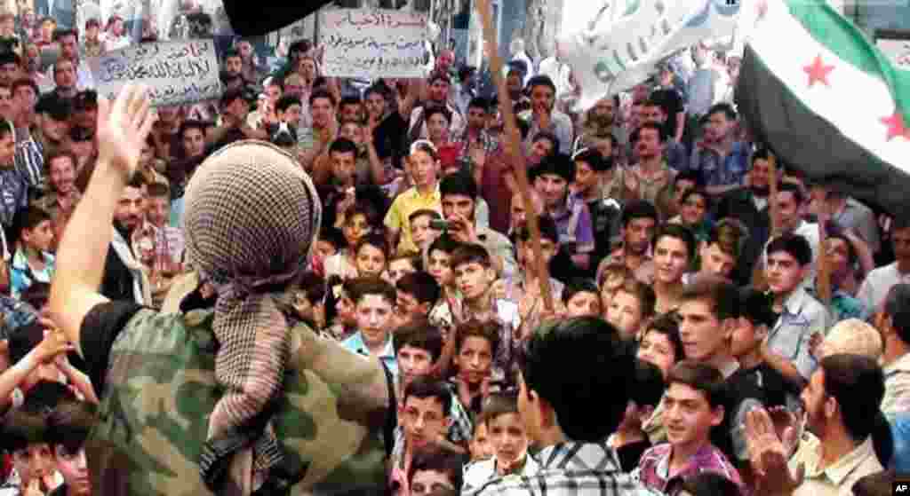 In this citizen journalism image provided by the United media office of Arbeen, a Syrian protester chants slogans during a demonstration in Arbeen, a suburb of Damascus, Sept. 13, 2013. 