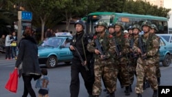 Policemen and paramilitary policemen patrol a street near the Kunming Railway Station, March 3, 2014.