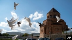 Pigeons fly near Holy Mother of God Cathedral in Stepanakert during a military conflict in the separatist region of Nagorno-Karabakh, Oct. 9, 2020. Armenia and Azerbaijan say they have agreed to a cease-fire.