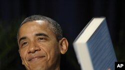 President Barack Obama holds up a book that he was given by author and keynote speaker Eric Metaxas, at the National Prayer Breakfast in Washington, February 2, 2012.