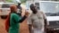 FILE - A health worker uses a thermometer to screen a man at a makeshift road block run by Guinean security forces outside the town of Forecariah, Guinea.