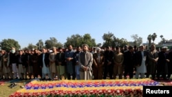 Afghan men pray near the coffin of journalist Malalai Maiwand, who was shot and killed by unknown gunmen in Jalalabad, Afghanistan, Dec. 10, 2020.