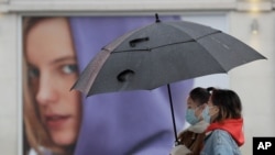 People wear masks to protect against coronavirus as they pass a shop in London, Feb. 3, 2021.