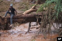 A man sits on a tree trunk in flooded Kamuchiri village, Kenya, on April 30, 2024. Kenya has been overwhelmed by flooding that killed 66 people on Monday alone and in recent days has blocked a national highway, swamped the main airport and swept a bus off a bridge.
