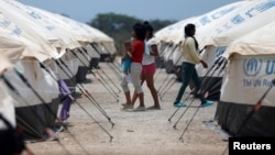 FILE - Venezuelan migrant women walk through a camp run by the U.N. refugee agency UNHCR in Maicao, Colombia, May 7, 2019. 