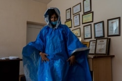 Jasmine Khachatryan, who heads a kindergarten that is now being used as a temporary shelter, wears a homemade poncho volunteers made to donate to soldiers on Oct. 8, 2020, in Goris, Armenia. (Yan Boechat/VOA)