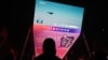 FILE - A man watches a news program about Chinese military drills surrounding Taiwan, on a giant screen outside a shopping mall in Beijing, on Oct. 14, 2024.
