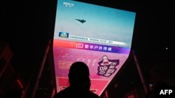 FILE - A man watches a news program about Chinese military drills surrounding Taiwan, on a giant screen outside a shopping mall in Beijing, on Oct. 14, 2024.