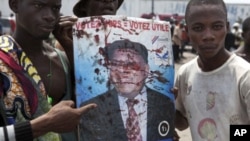 Opposition UDPS members hold up blood-splattered poster of leader Etienne Tshisekedi after presidential guard opened fire on crowd outside N'Djili airport in Kinshasa, November 26, 2011.