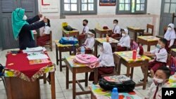 Siswa mengenakan masker untuk membantu mencegah penyebaran COVID-19 menghadiri kelas tatap muka pada hari pertama pembukaan kembali sekolah di di Jakarta, Senin, 30 Agustus 2021. (Foto: AP)