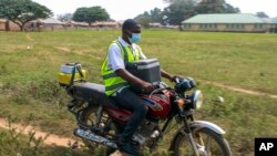 FILE - Yunusa Bawa, a community health worker, rides on a motorbike with a box of AstraZeneca coronavirus vaccines, in Sabon Kuje on the outskirts of Abuja, Nigeria, Dec 6, 2021.