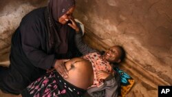 Lucy Mbewe, a traditional birth attendant attends to a pregnant woman at her home, in Simika Village, Chiradzulu, southern Malawi on Sunday, May 23, 2021. 