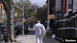 People wear face masks for protection against the coronavirus as the walk their dog on the Brooklyn Bridge in New York, April 10, 2020.