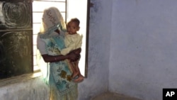 Phul Kumari, 25, stands with her child in a village community center in Baghpat district, in India's northern state of Uttar Pradesh October 18, 2011. Kumari was trafficked to Uttar Pradesh as a bride for her husband and has been repeatedly raped by his 