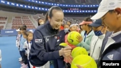 Petenis Tiongkok Peng Shuai menandatangani bola tenis berukuran besar pada upacara pembukaan Final Penantang Tenis Junior Fila Kids di Beijing, China, 21 November 2021, dalam tangkapan layar yang diperoleh dari video media sosial. (Twitter @QINGQINGPARIS melalui Reuters)