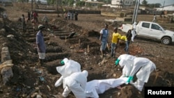 Health workers bury the body of a suspected Ebola victim at a cemetery in Freetown, Dec. 21, 2014. 